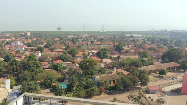 A Lush Residential Area With Rooftops and a Serene Waterway in Guinea-Bissau, West Africa - Aerial Drone Shot