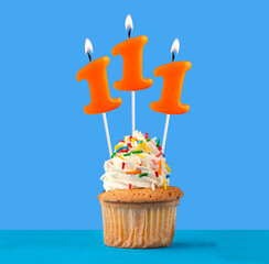 Orange candle number 111 - Birthday cupcake on blue background