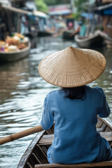 Fototapeta premium Vietnamese woman wearing conical hat rowing on river at floating market