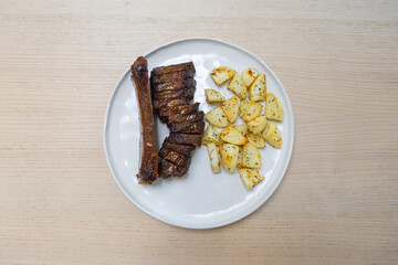 A plate of beef ribs and potato.