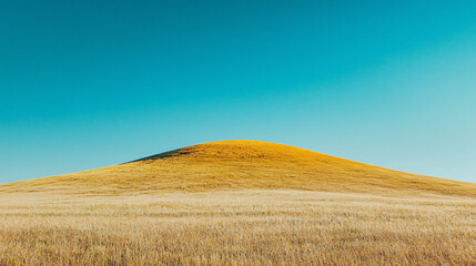 Fototapeta premium Lush golden hill under a clear blue sky, showcasing nature's beauty in a serene landscape