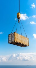 Crane lifts container over ocean; sunny day