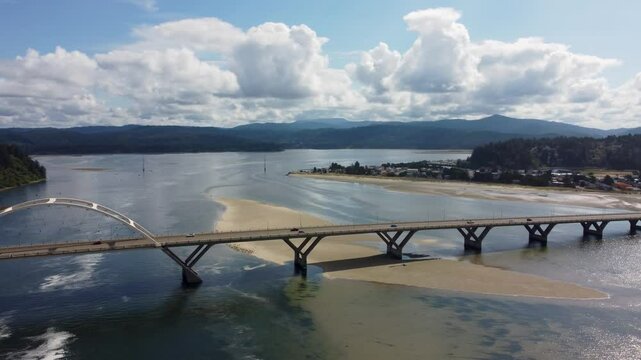 Alsea Bay Bridge spanning the Alsea River in Waldport, Oregon, along HWY 101. Cars Driving Across Bridge Crossing on Summer Day Pan to Bayshore. South of Newport, North of Florence and Yachats