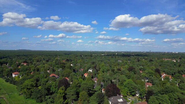 nikolassee, a residential district in berlin, featuring houses nestled within a dense forest, with the city skyline visible on the horizon. Best aerial view flight speed ramp hyper motion time lapse