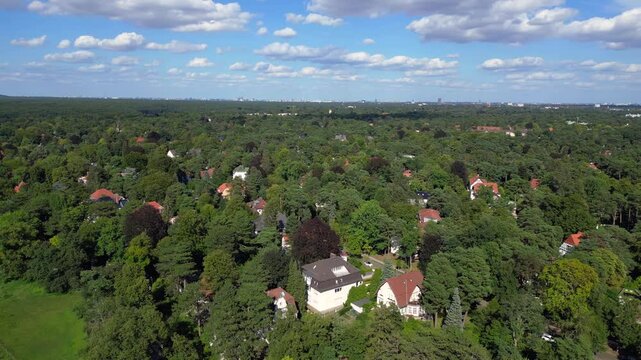 nikolassee, a residential district in berlin, featuring houses nestled within a dense forest, with the city skyline visible on the horizon. Unbelievable aerial view flight rotation to right drone
