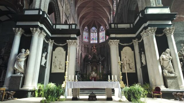 Ornate altar inside Saint Bavo's Cathedral in Ghent, Belgium, featuring statues, columns, and stained glass windows