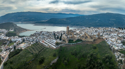 Aerial view of Iznajar castle white village in Andalucia, triangular design, wall with flanking towers, pentagonal keep in Spain above a reservoir