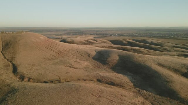 Dry hills and valleys at sunset near a small town