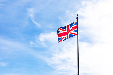 Mockup Union Jack Flag Of The United Kingdom Flying On A Flagpole Against A Minimalistic Blue Sky, Symbolizing British Culture, Heritage, And Patriotism. Travel, Cultural, Or Educational Uk Project