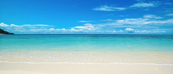 Panoramic view of a beautiful beach with white sand turquoise ocean water and a blue sky with clouds on a sunny day ideal for summer vacation themes. Made with generative AI