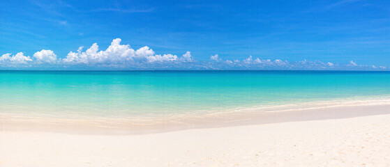 Panoramic view of a beautiful beach with white sand turquoise ocean water and a blue sky with clouds on a sunny day ideal for summer vacation themes. Made with generative AI