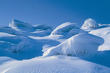 Snow-covered landscape with icy formations under a clear blue sky, evoking tranquility and winter beauty