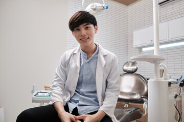 Portrait of one young smart Asian male dentist in uniform, Thai professional dental occupation...