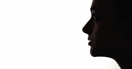 Faithful face. Anxious hope. Dark contrast profile silhouette of disturbed worried woman isolated on white empty space background.
