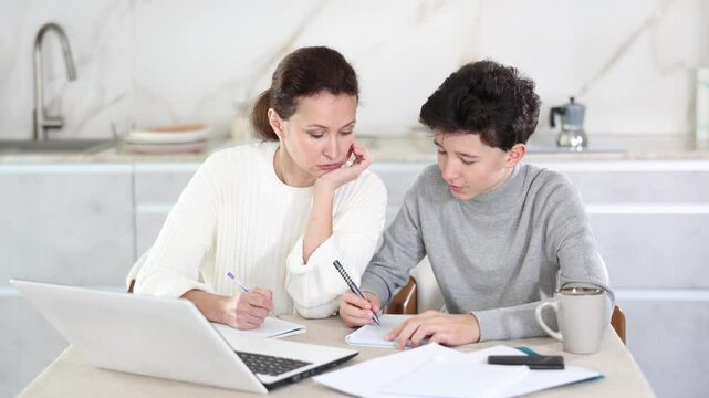 Boy and his mother study via video conference using a laptop in kitchen. High quality 4k footage