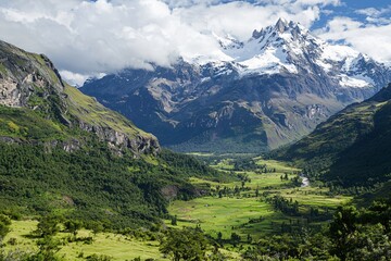 Fototapeta premium Majestic mountain landscape with snow-capped peaks, lush green valleys, and a serene river flowing