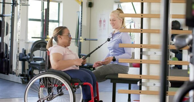 Exercising with resistance band, woman with paraplegia in wheelchair with therapist, rehabilitation