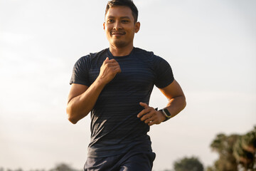 A male athlete enjoys a morning run in the park, smiling and exercising outdoors. Embracing fitness...