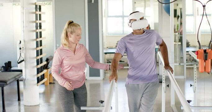 Man in prosthetic leg using VR headset with therapist on parallel bars