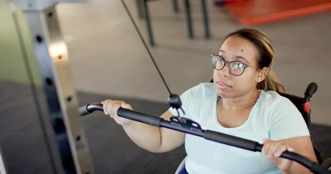 woman in wheelchair with paraplegia exercising with cable machine in rehabilitation gym