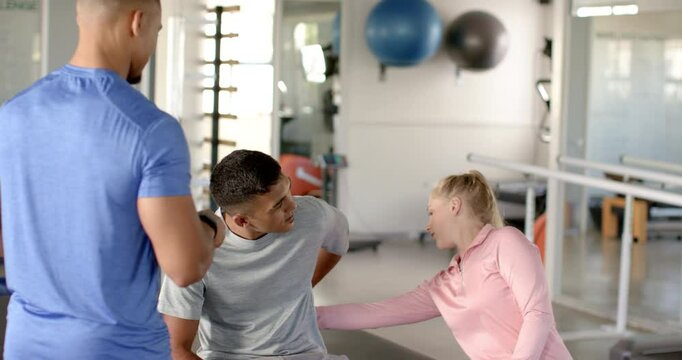 In disability rehab, therapist assisting man with back pain during physical therapy