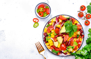 Mexican vegan corn salad with red beans, avocado, tomatoes, onion and cilantro. White background, top view