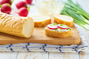 Sliced baguette with soft cheese, radish and freshly chopped chives in a plate. healthy diet snacks. close up.