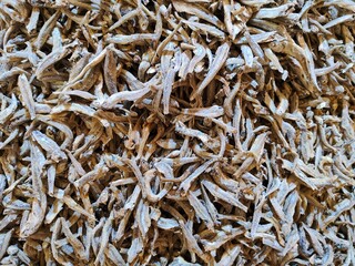 Close-up of dried anchovies in a textured pile for culinary and market use