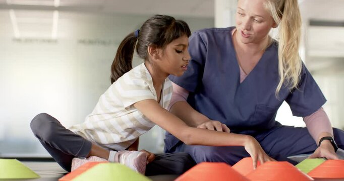 Playing with colorful cones, girl with cerebral palsy in rehabilitation focusing with therapist