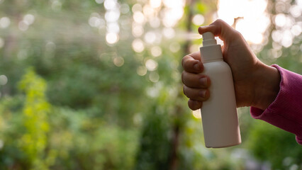 Hand applying insect repellent mosquito insecticide spray to kill flies bugs and mosquitoes on skin...