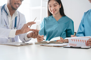 Fototapeta premium Two male doctors and a female nurse meet at a table in the hospital, collaborating on medical tasks, using laptops and computers, showcasing teamwork,and focusing on health,medicine,and patient care