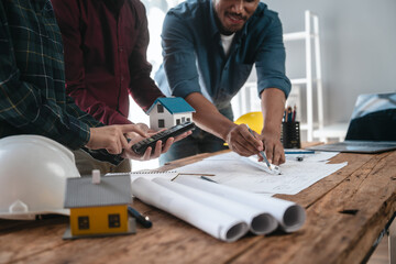 Two male engineers and a strong woman discuss blueprints and home design at a table. They work as a professional team, collaborating on construction projects with precision and expertise