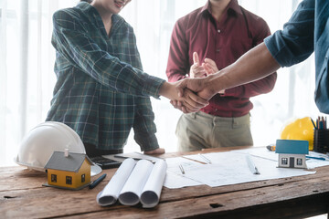 Two male engineers and a strong woman discuss blueprints and home design at a table. They work as a professional team, collaborating on construction projects with precision and expertise