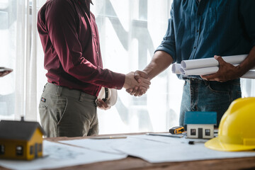 Two male engineers and a strong woman discuss blueprints and home design at a table. They work as a professional team, collaborating on construction projects with precision and expertise