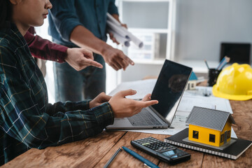 Two male engineers and a strong woman discuss blueprints and home design at a table. They work as a professional team, collaborating on construction projects with precision and expertise