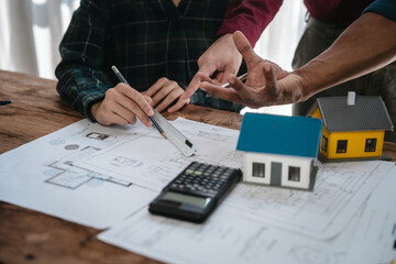 Two male engineers and a strong woman discuss blueprints and home design at a table. They work as a professional team, collaborating on construction projects with precision and expertise