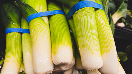 macro close-up of green leeks bundled and stacked on the market shelf full frame vegetable food...