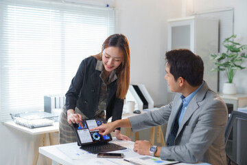 Asian businesspeople analyzing financial charts and graphs on tablet in office