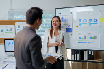 Asian businesspeople discussing company performance analyzing charts on whiteboard