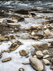 stones and ice on the bank of a mountain river in winter