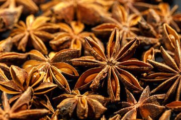 Anise stars texture background, above view close up flavor spices dried anise seeds on dark, still...