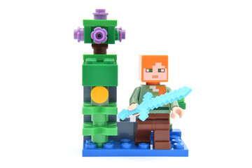 Naklejka premium Lego minifigure of Alex from popular game Minecraft with pixel sword isolated on white. Editorial illustrative image of popular plastic toys.