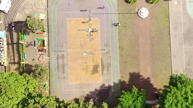 Drone Footage of Football Game on futsal field. Top view of boys having fun playing football in Cicalengka Square. Playing ball on cement field. Sports Activity. Aerial shot in 4K Resolution.