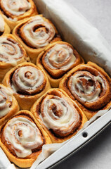 Freshly baked cinnamon rolls drizzled with icing in a baking pan