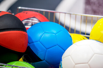 Soccer ball and volleyball in shopping cart in the sports shop. Sports equipment shopping.