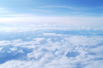 Aerial view of a stunning snow-covered mountain range surrounded by clouds during daylight with clear blue skies