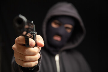 Robber with balaclava holding gun. Armed hooded killer Weapon, crime concept