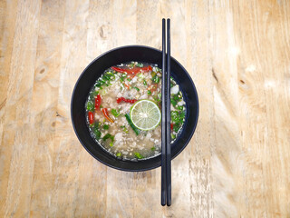 Spicy Pork Back-Bone Stew topped with sliced ​​green and red chili peppers,  garlic.thai food cusine on  wood table.