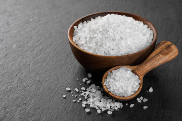 sea salt in bowl and in spoon on black stone background