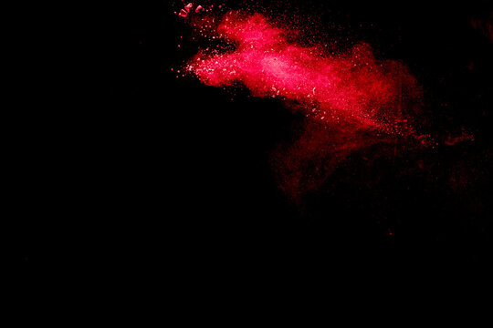 Red dust particles explosioon on black background.Red powder splash.
